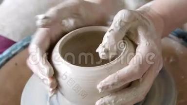 女人用她的双手托起壁壶，在圆圈上用粘土雕刻